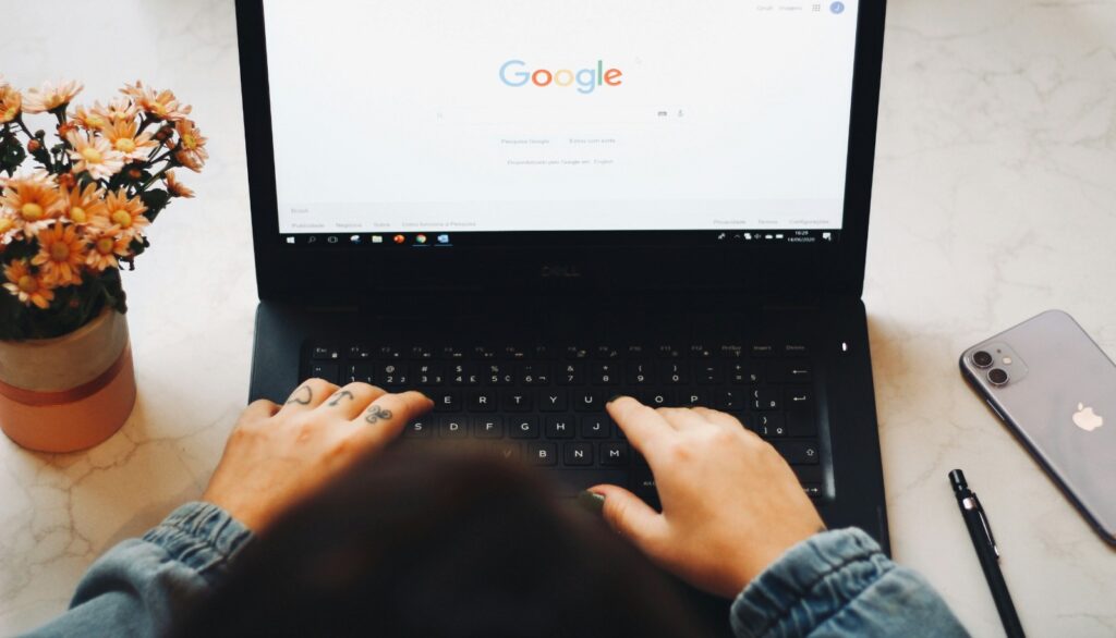 Woman typing on a laptop while the Google homepage is displayed
